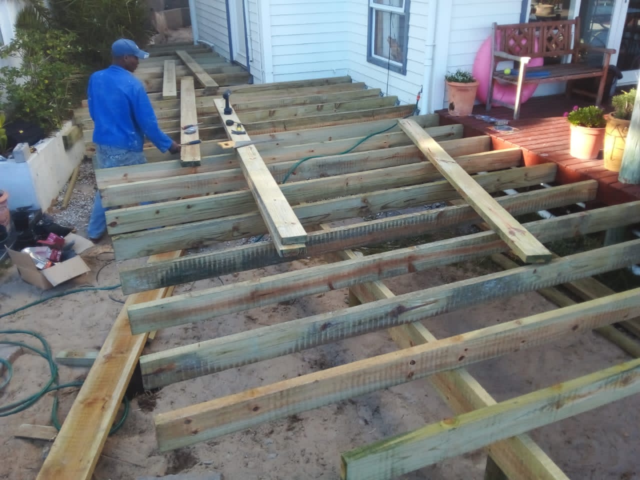 Workers installing timber deck joists beside a house