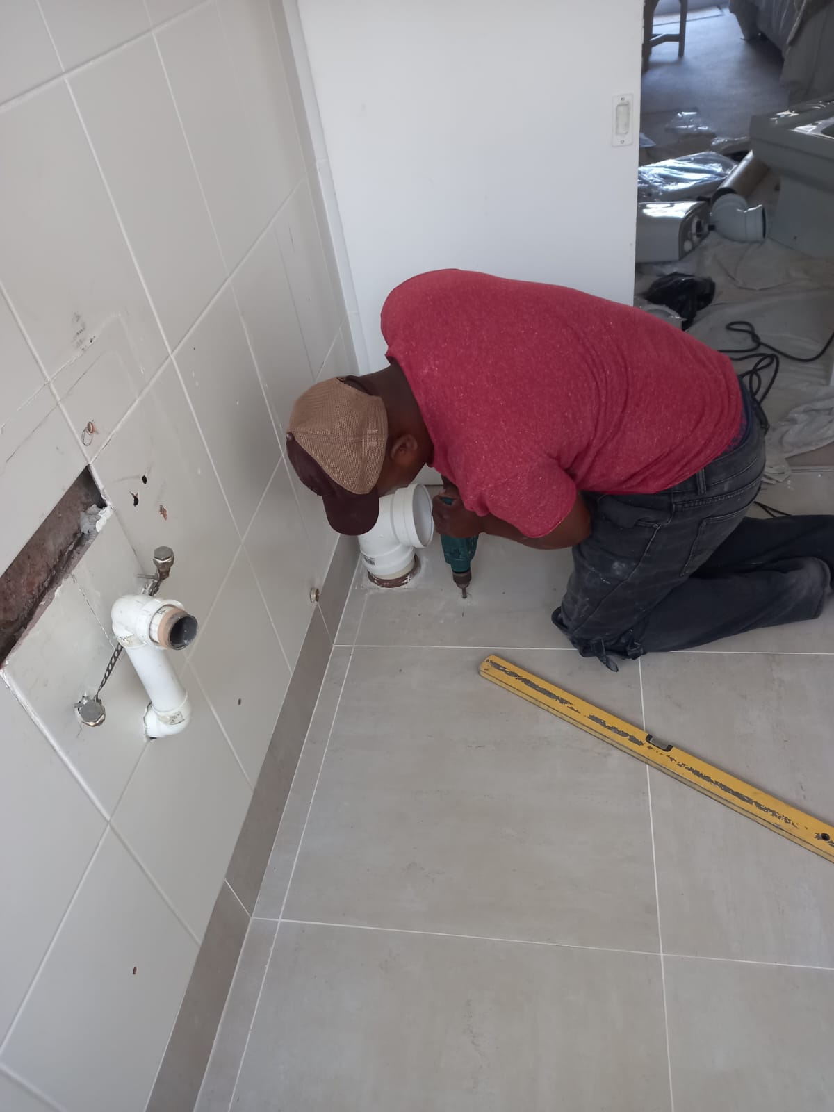 Worker installing bathroom plumbing at low wall outlets