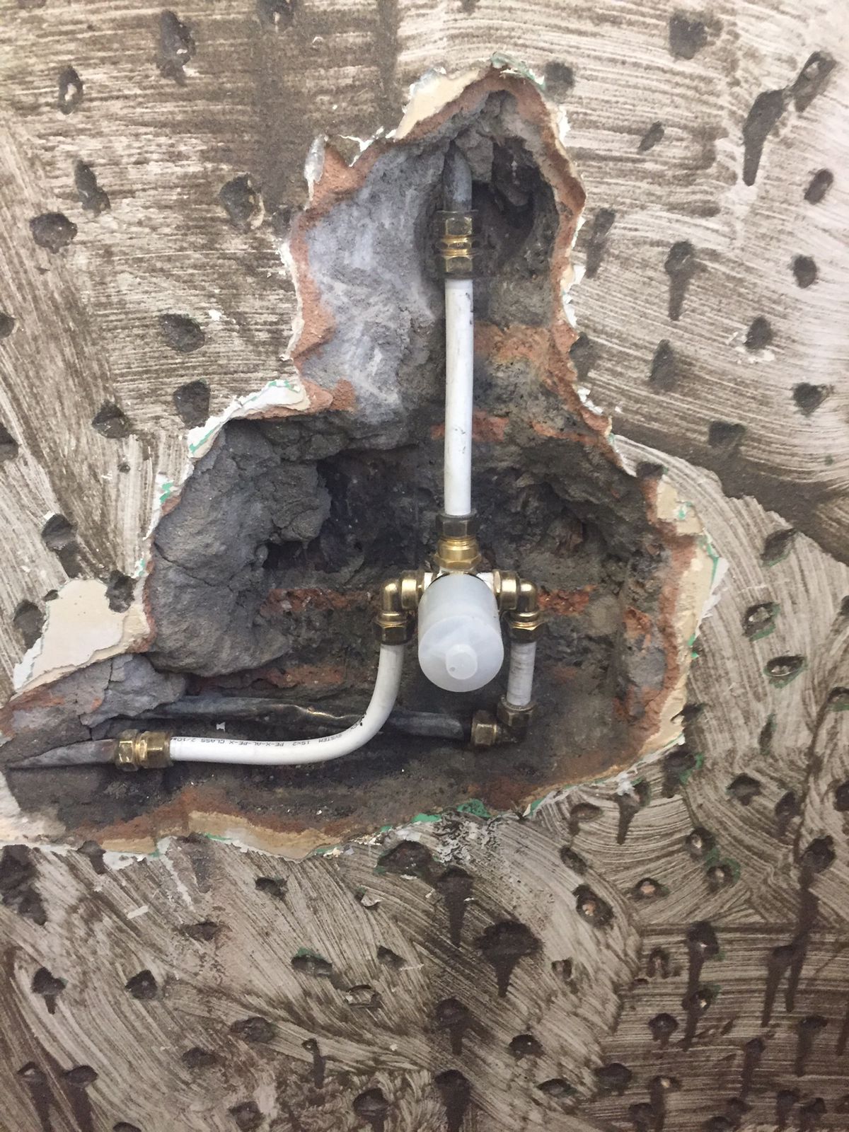 Plumbing repair exposed in chased masonry with pipes visible
