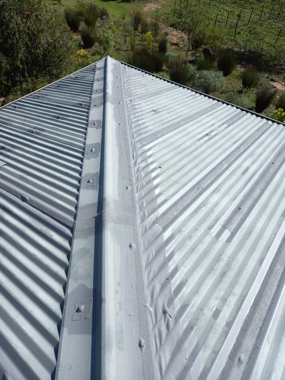 Corrugated metal roof with sealed ridge and sheet joints
