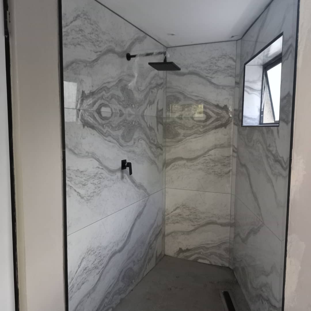 Walk-in shower with marble-pattern wall tiles and overhead shower