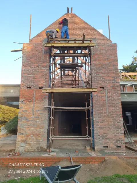 Double-storey brick house under construction with scaffolding