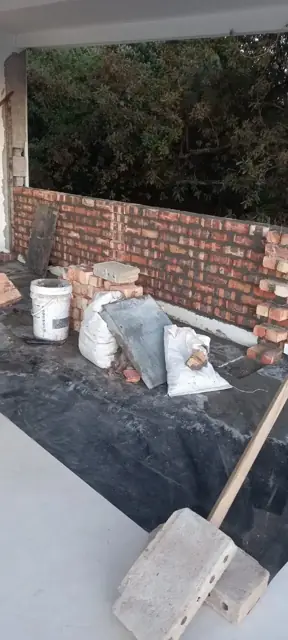 Brick wall under construction with mortar and tools