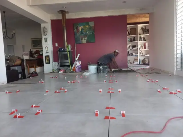 Floor tiles set out with levelling clips across a living room