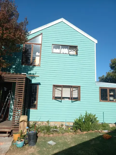 Timber-clad double-storey house part-painted teal