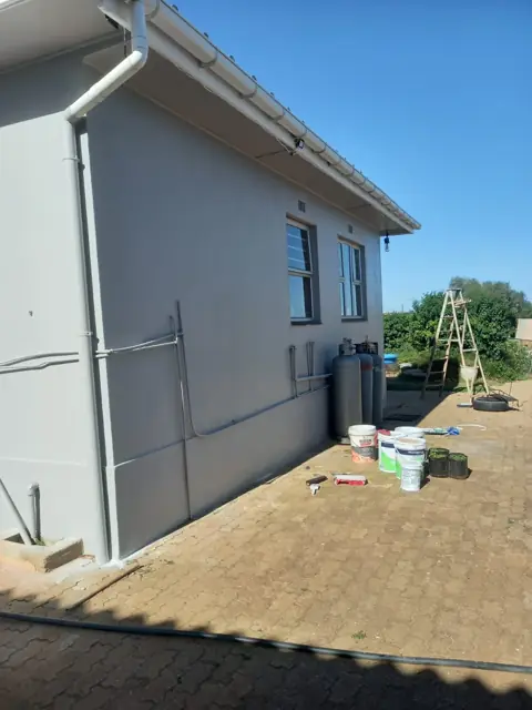 Painted house exterior with paint tins and ladder on site