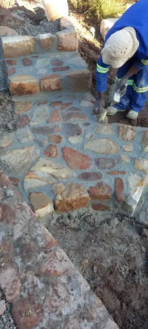 Stonemason laying stone cladding on garden steps