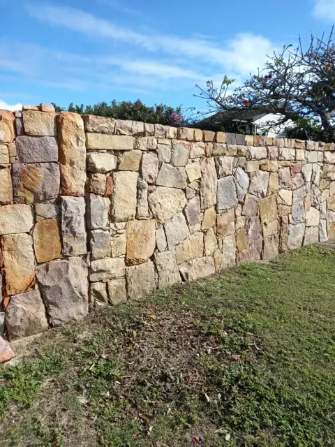 Long natural stone boundary wall in a garden