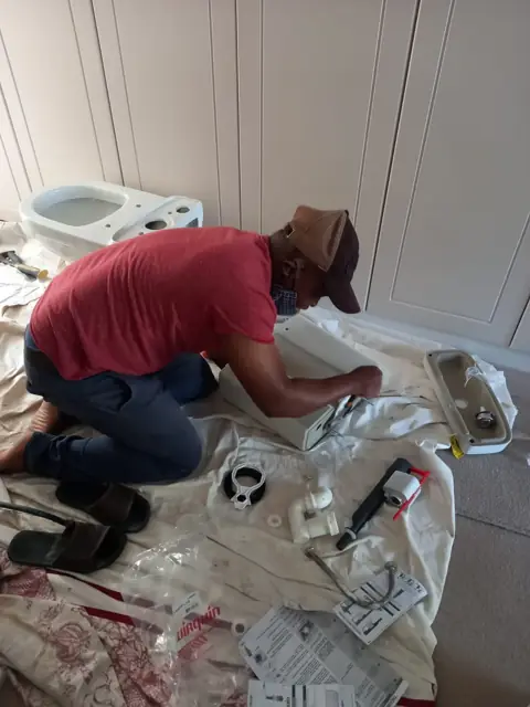 Plumber fitting a basin on a dust sheet