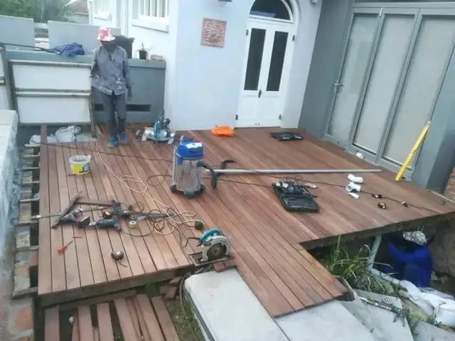 Workers constructing a timber deck, boards and tools laid out