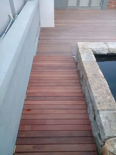 Timber deck walkway alongside a stone-edged garden pond