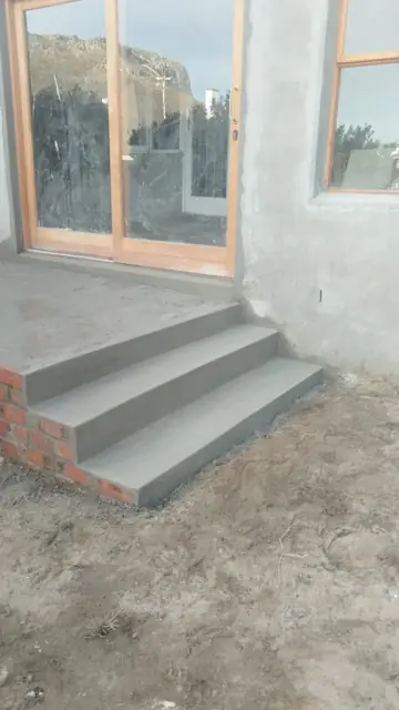 Freshly plastered exterior wall with timber window and new concrete steps