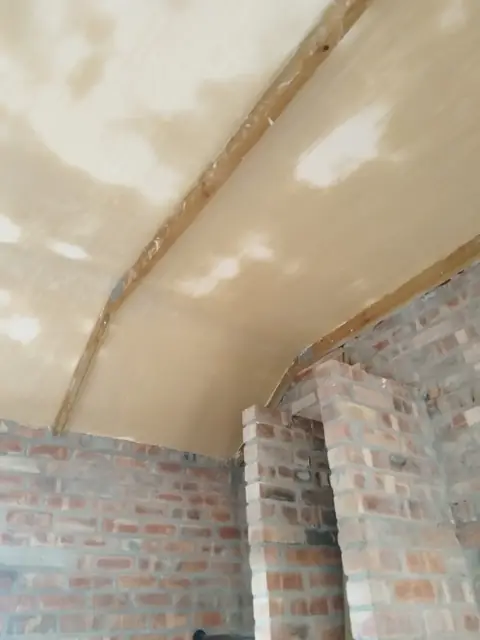 Skimmed vaulted ceiling above brick wall