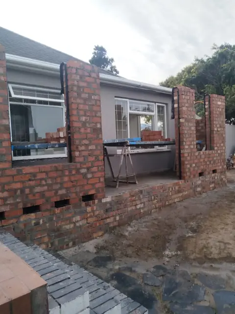 Brick extension walls rising in front of existing house