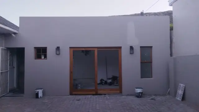 Finished white-painted rear elevation with timber doors and windows; alt new building