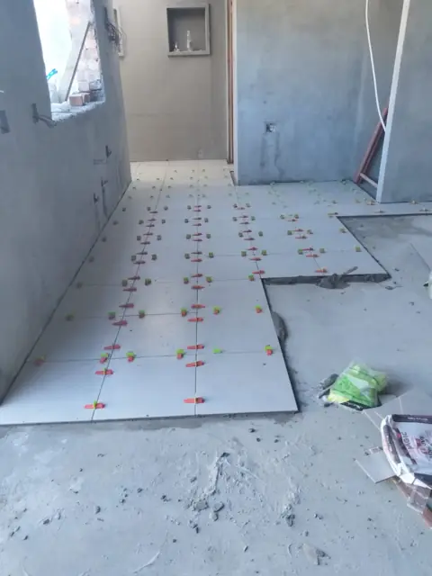 Large grey floor tiles being laid with levelling clips
