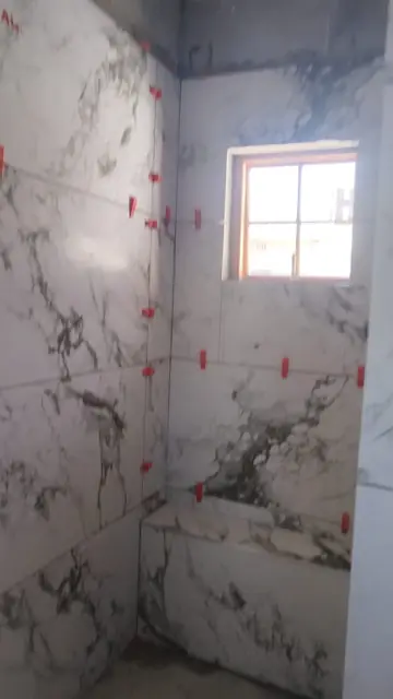 Marble-look wall tiles with levelling clips in a bathroom