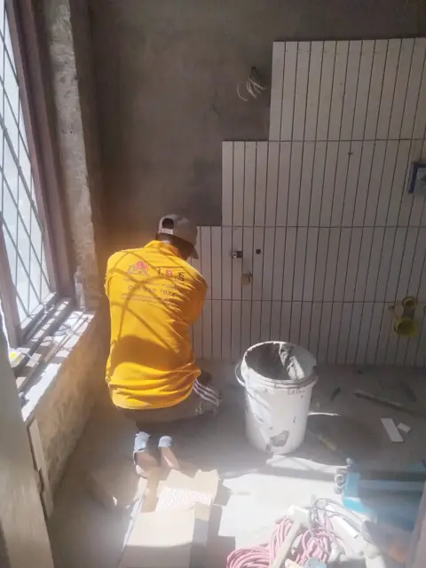 Tiler fixing white wall tiles beside a window