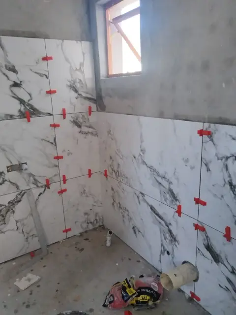 Marble-look wall tiles with levelling clips around a window