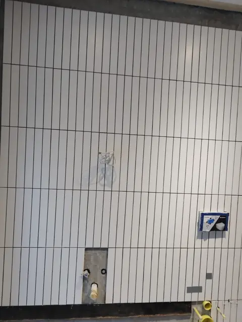 White vertical stack tiles with cut-outs for plumbing fittings
