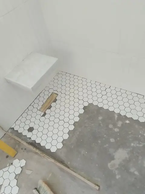Hexagon mosaic floor tiles partially laid in a bathroom