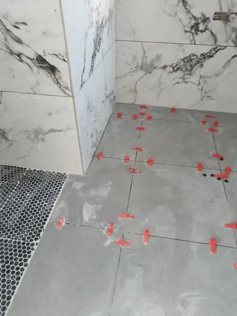 Marble-look wall tiles and penny mosaic floor with levelling clips