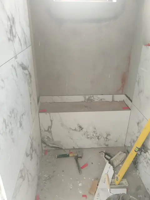 Marble-look tiled shower with built-in bench