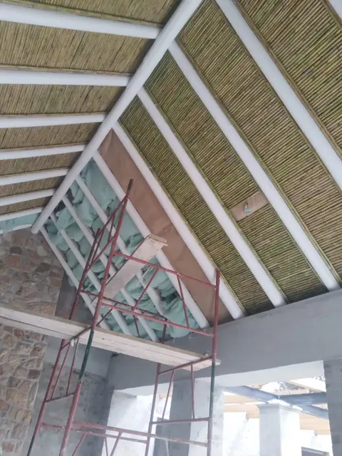 Reed ceiling panels and insulation fitted between roof beams