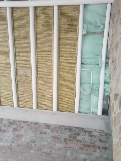 Reed ceiling panels with insulation between white-painted beams