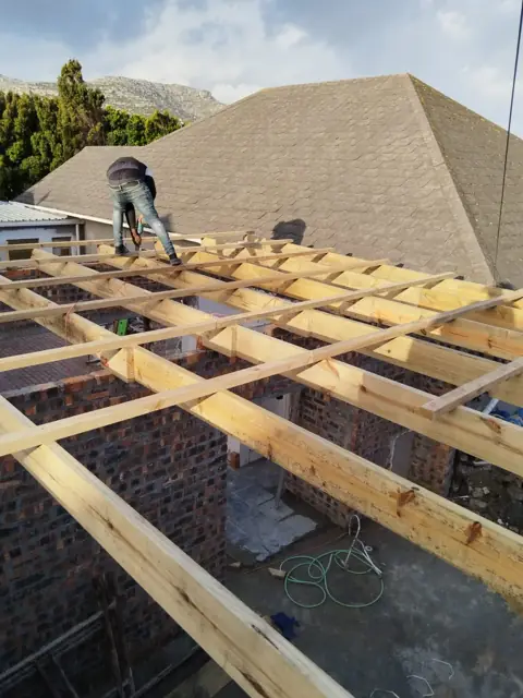 Timber roof trusses and battens being built over a brick garage