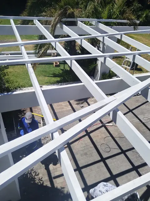 White pergola roof grid seen from above the patio