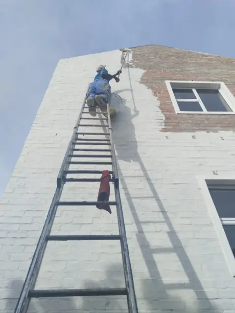 Exterior wall painting on high gable via ladder