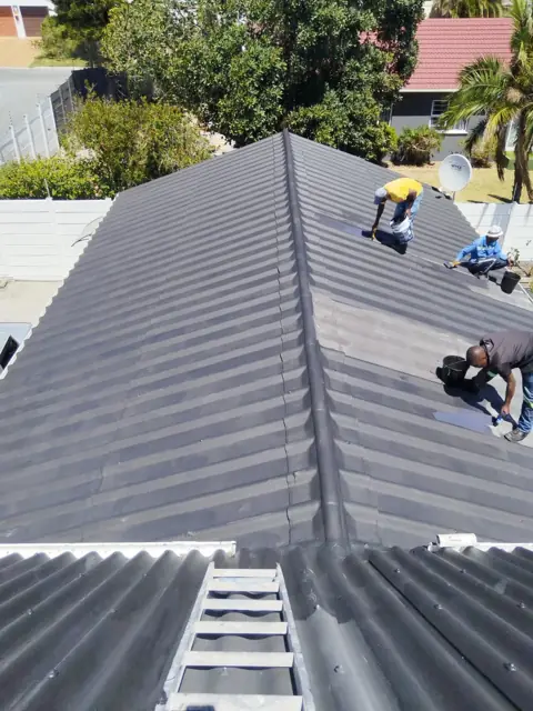 Team coating roof ridge on corrugated roof