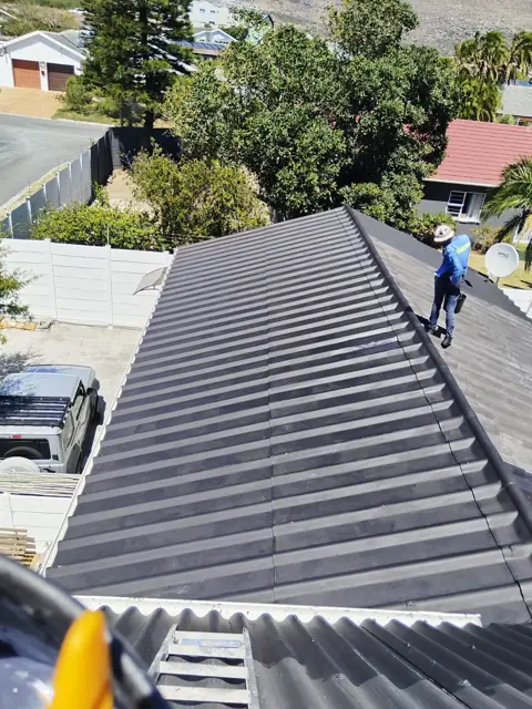 Roof recoating from above, worker on ridge