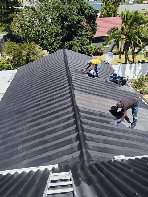 Roofing team coating a long roof
