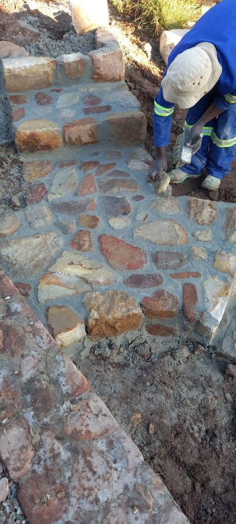 Stonemason laying stone cladding on garden steps — stone cladding prices