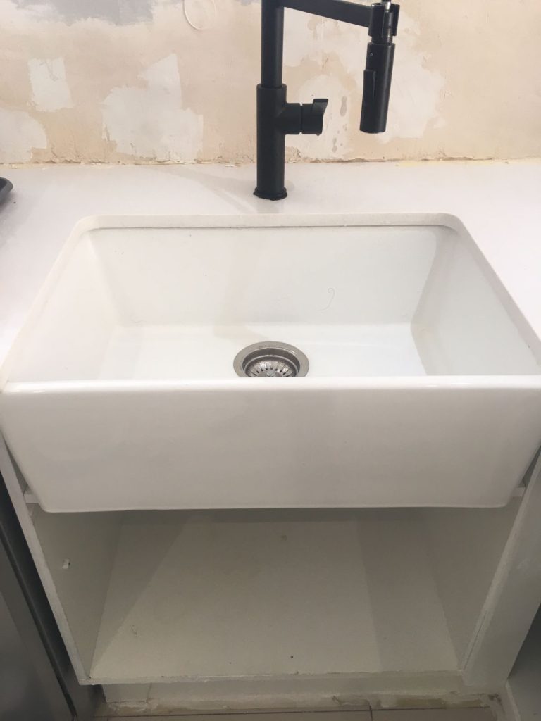 Butler sink fitted with black mixer tap, wall stripped — registered plumbers near me