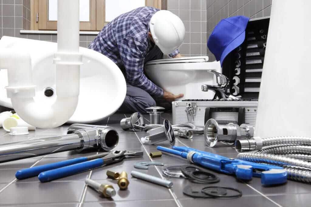 Plumber at work with bathroom fittings and tools