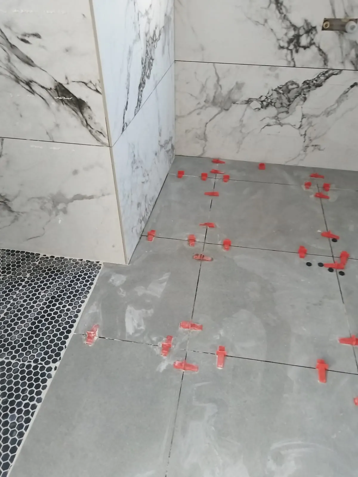 Marble-look wall tiles and penny mosaic floor with levelling clips